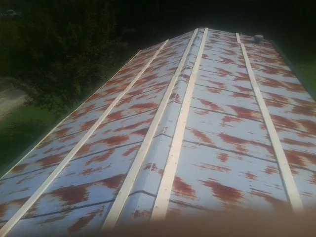Rusted metal roof panels with new wood purlins before replacement — Storm Damage Roof Repair in Shenandoah Junction by Roofing Brothers