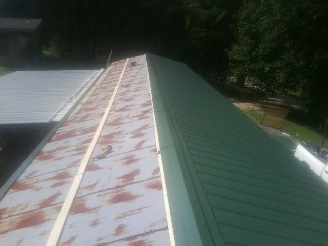 Old rusted panels beside newly installed green metal roofing — Wind Damage Roof Repair by Roofing Brothers in Shenandoah Junction