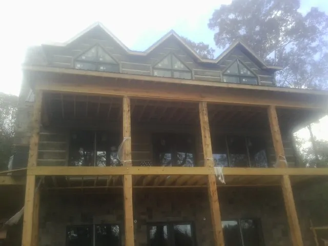 Dormers and porch framing on a large log home under construction — Roof Coating work by our crew in Shenandoah Junction