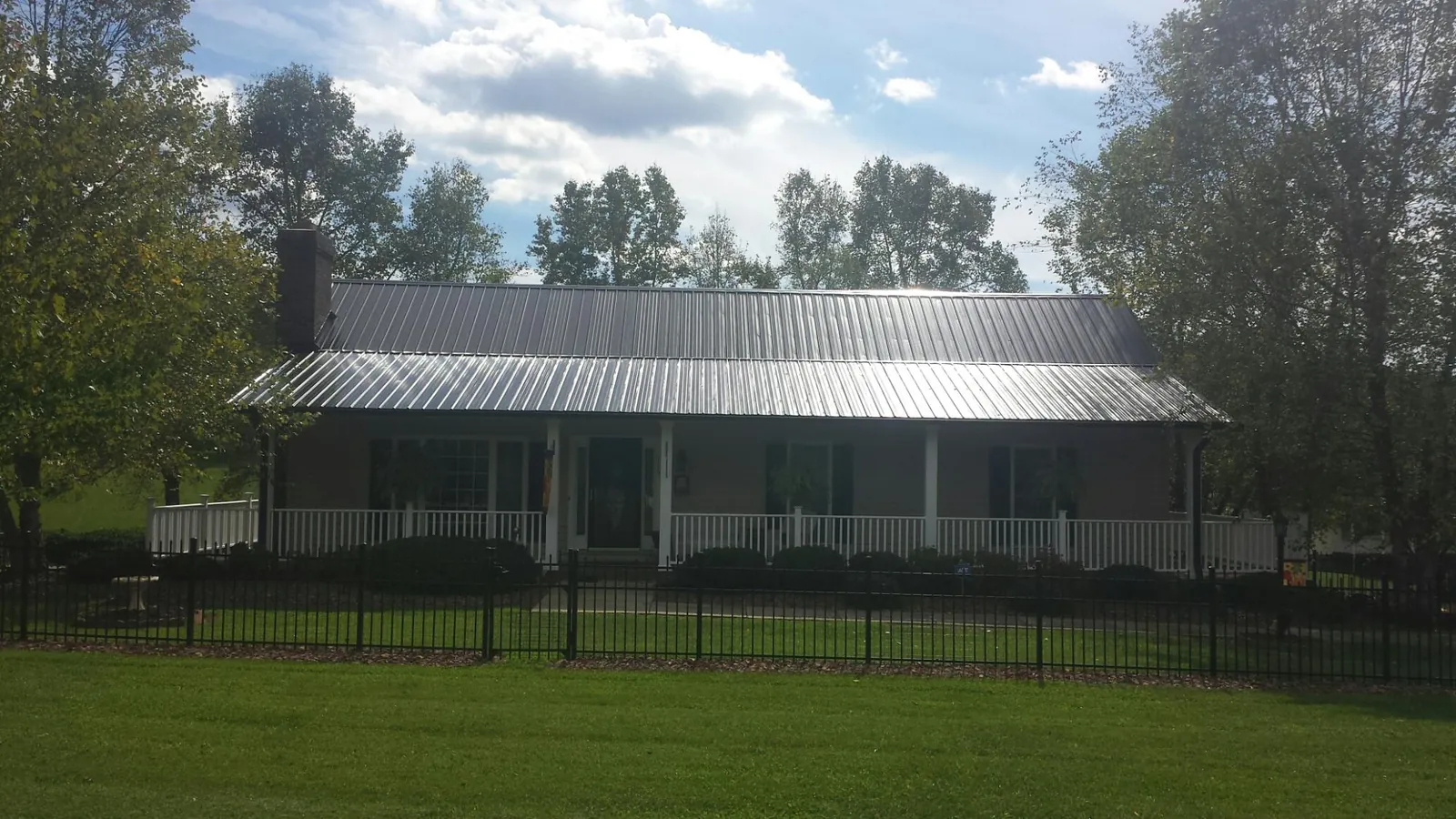 Gray metal roof on a brick ranch with a full width front porch — Gutter Guard Installation work by our crew in Shenandoah Junction