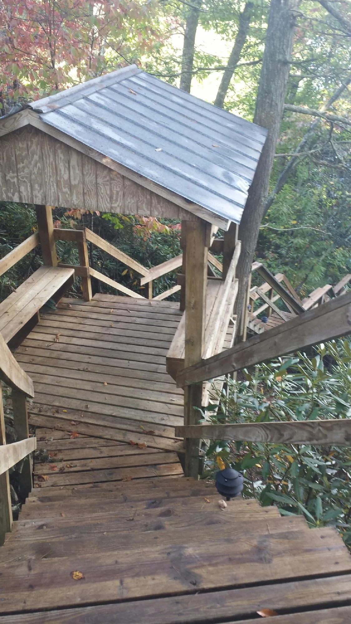 Metal roofed shelter over wooden steps on a wooded walkway — Skylight Repair & Installation work by our crew in Shenandoah Junction