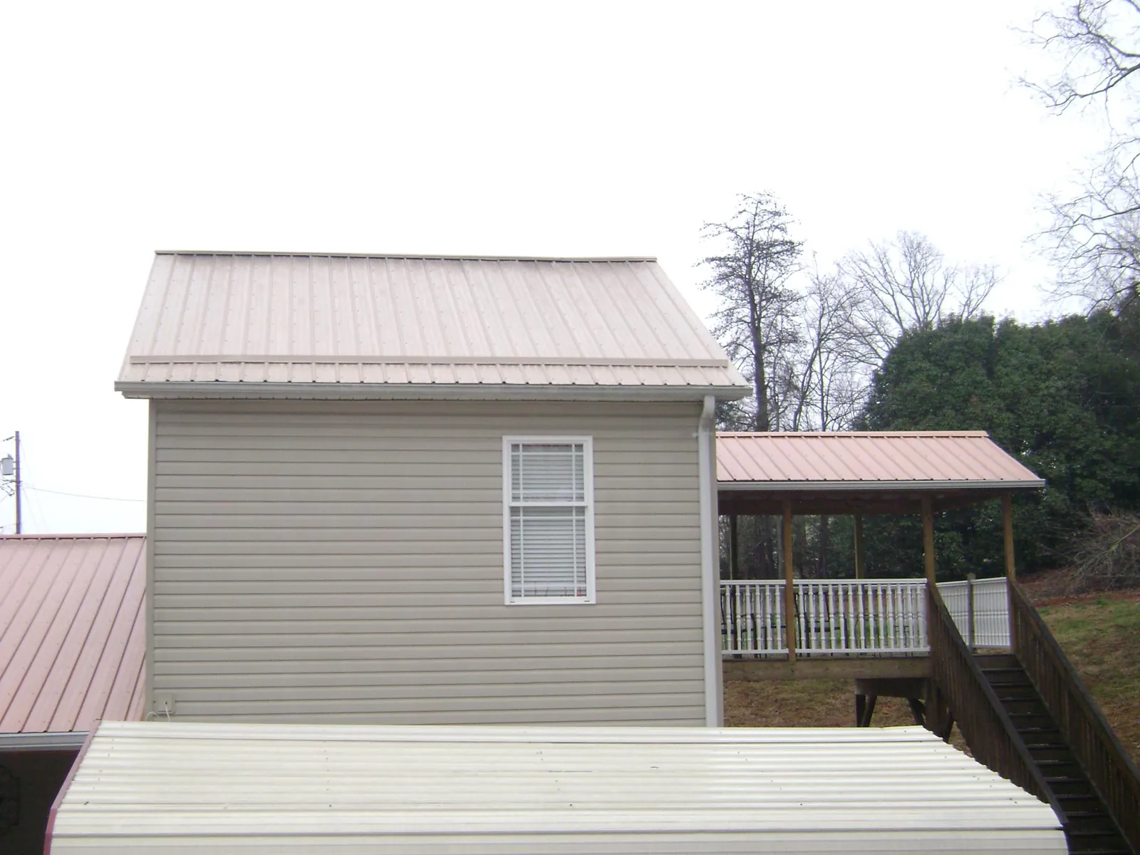 Tan metal roofs on a two story addition and attached porch, from a Roof Replacement job in Shenandoah Junction