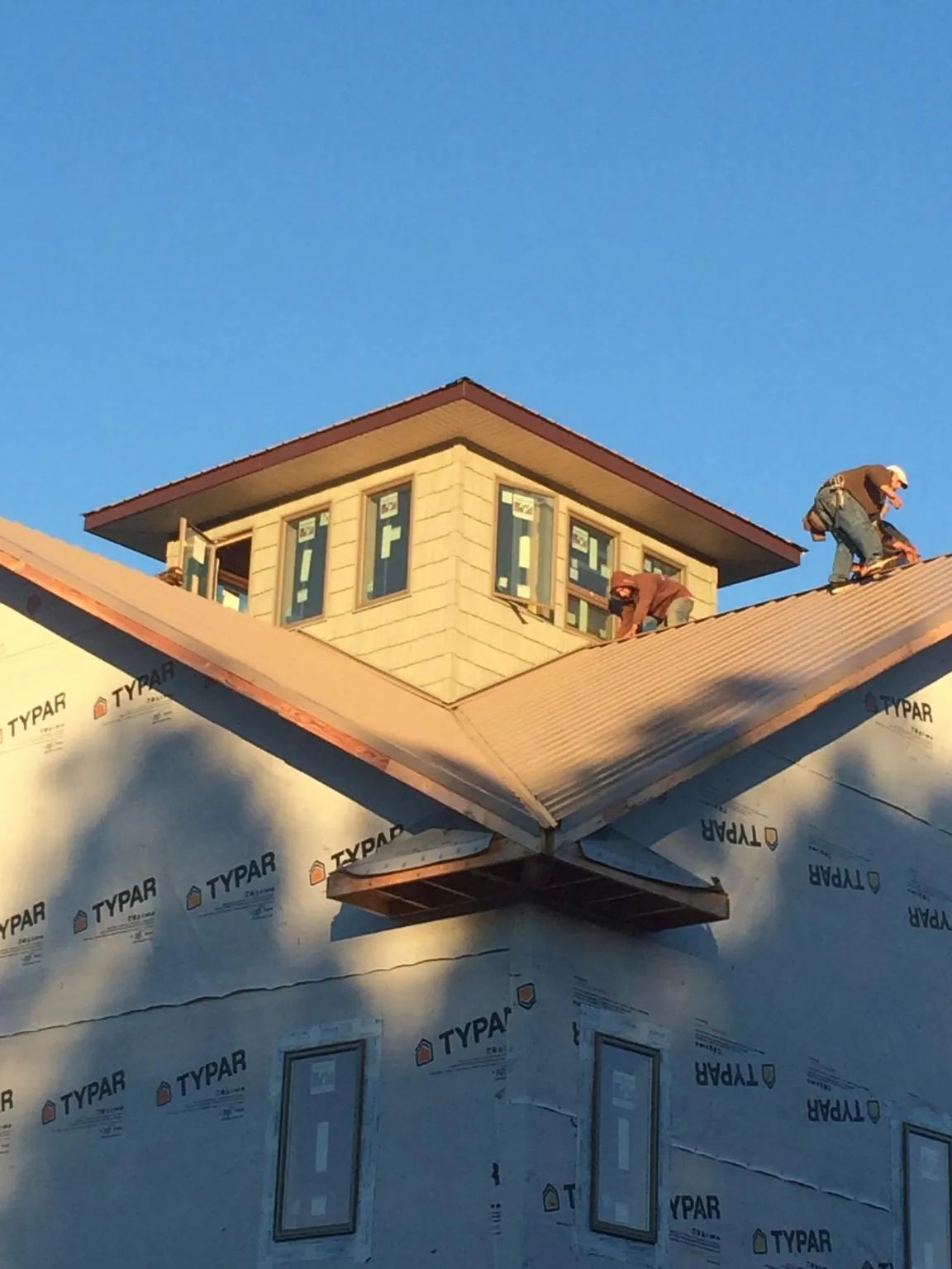 Roofers working around a rooftop cupola on a new metal roof at sunset — Roof Waterproofing in Shenandoah Junction by Roofing Brothers